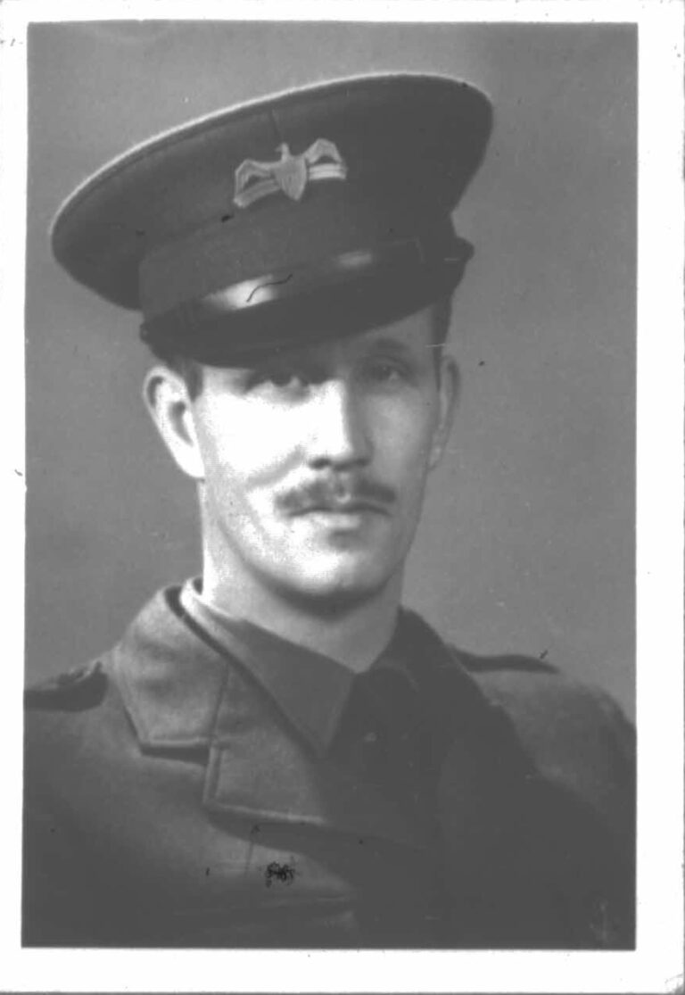 A black and white portrait of a man seen from the chest up in military uniform. He wears a cap with an eagle emblem and has a light mustache. He looks at the camera and has soft, inviting expression. The background is plain.